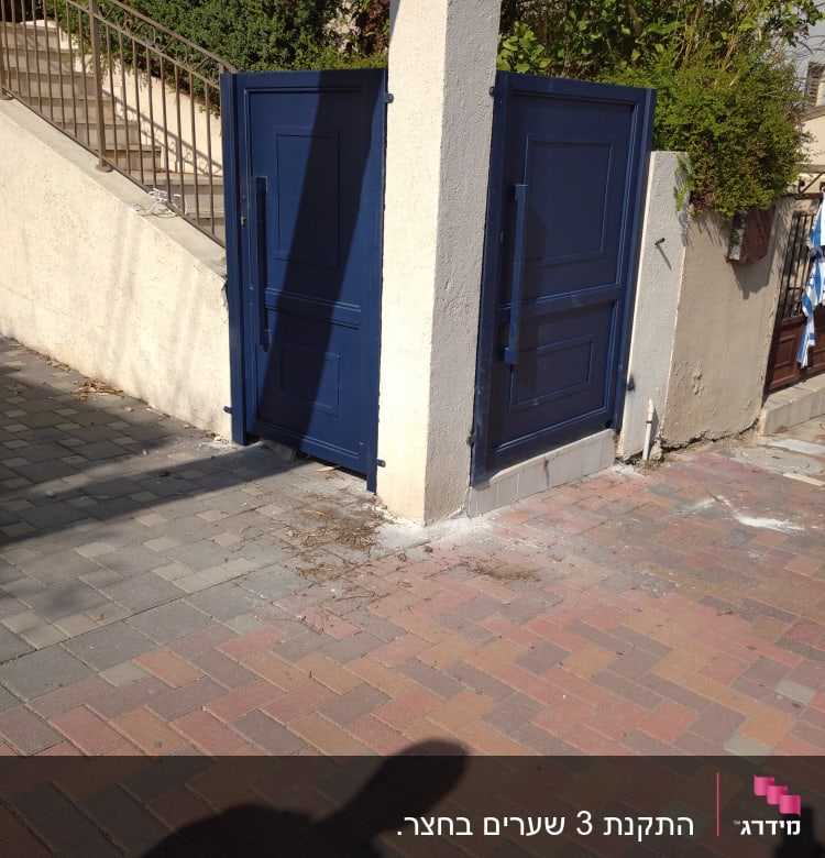 שני שערים כחולים פתוחים על עמוד בטון